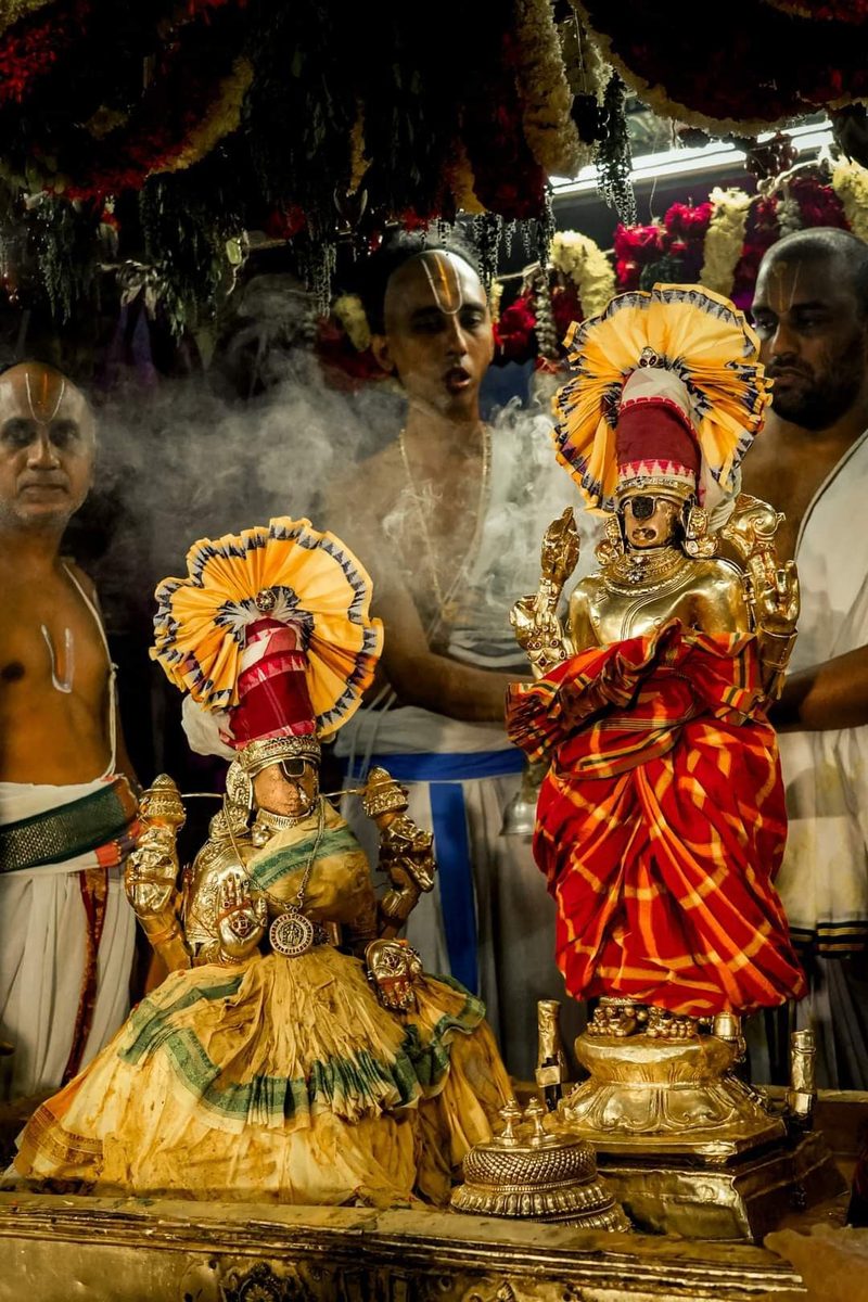 Deities adorned with gold, flowers and silk during a temple ceremony